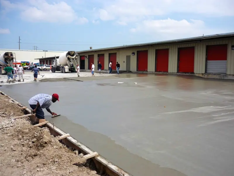 Finisher working a large commercial slab in front of a row of storage units