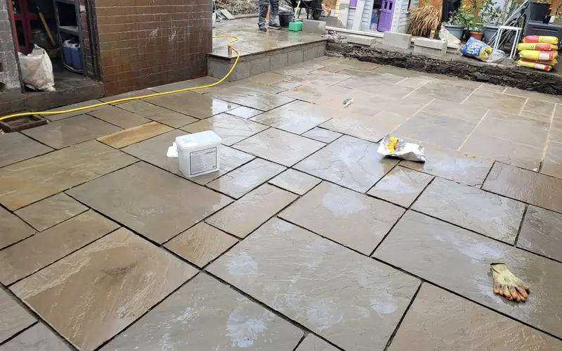 Large-format stone patio slabs being set in a backyard