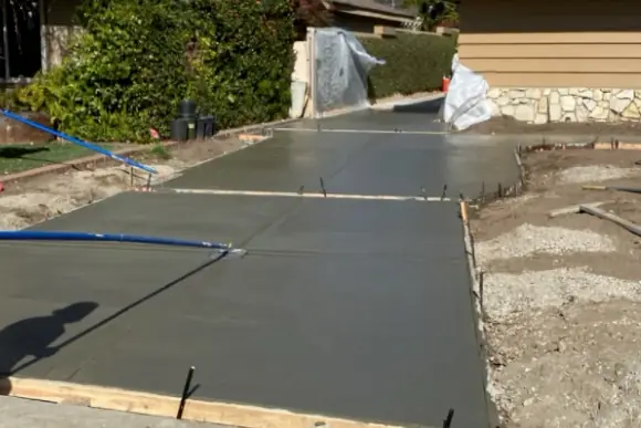 Fresh concrete slab still in its wood forms, with control joints cut in