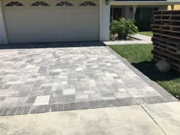 Gray paver driveway in a running pattern leading to a garage