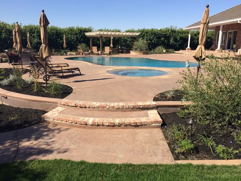 Colored concrete pool deck and wide curved steps leading down to the pool