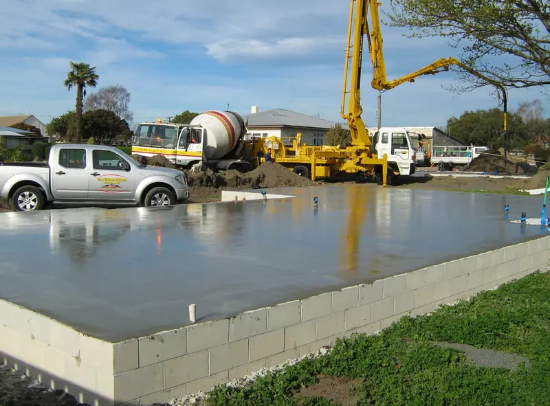 Freshly poured slab beside a concrete pump truck and mixer