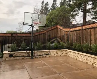 Stained concrete backyard slab with a block planter wall and basketball hoop