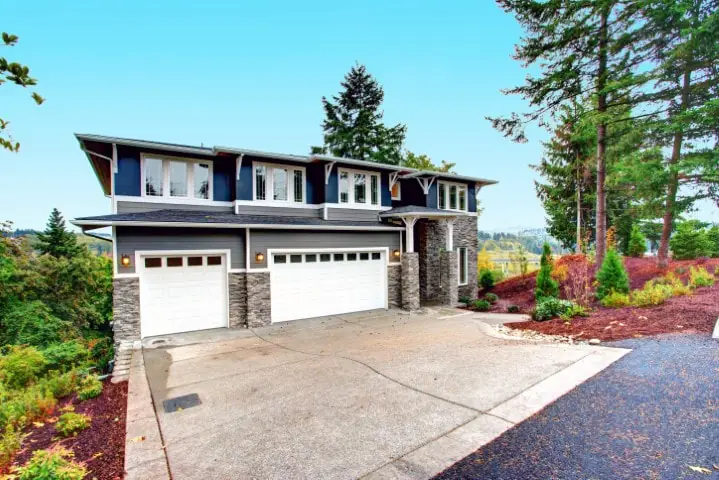 Wide new concrete driveway in front of a two-story home with a three-car garage